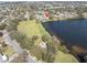 Aerial view of a lakeside home with a large lawn and community playground at 1230 75Th N Ave, St Petersburg, FL 33702