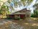 Charming two-story home with a rustic facade, red trim, and a landscaped front yard under a canopy of trees at 12950 Lincoln Rd, Riverview, FL 33578