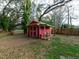 Red shed in the backyard featuring a charming design, small porch, and ample space, ideal for storage at 12950 Lincoln Rd, Riverview, FL 33578