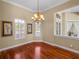 Elegant dining room featuring hardwood floors, large windows with plantation shutters, and a decorative chandelier at 13854 Thoroughbred Dr, Dade City, FL 33525