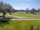 Scenic view of the lush green golf course with sand traps and a distant lake at 13854 Thoroughbred Dr, Dade City, FL 33525