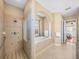 Elegant bathroom featuring a tiled walk-in shower and tub with a large picture window at 13854 Thoroughbred Dr, Dade City, FL 33525