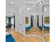Hallway with large mirrors, chandelier, white trim, hardwood floors, and a cozy blue bench at 2603 W Parkland Blvd, Tampa, FL 33609