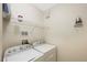 Functional laundry room with washer, dryer, and shelving unit at 2747 Via Capri # 1122, Clearwater, FL 33764