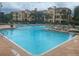 Resort-style pool with sun loungers and volleyball net, surrounded by the community's architecture at 2747 Via Capri # 1122, Clearwater, FL 33764