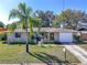 Charming single-story home featuring an attached garage, lush front lawn, and mature palm tree at 3054 Bright Dr, Holiday, FL 34691