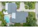 Aerial view of property featuring a backyard pool, lush landscaping, grey roof, and ample parking at 5114 N Branch Ave, Tampa, FL 33603