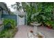 Lush tropical backyard with a pergola-covered gate, brick patio, a decorative fountain, and manicured greenery at 5114 N Branch Ave, Tampa, FL 33603