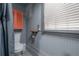 Well-lit bathroom with toilet, window, painted wood paneling, and storage cabinet at 5114 N Branch Ave, Tampa, FL 33603