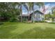 Charming blue home with a lush green lawn, palm trees, and an American flag waving in the breeze at 5114 N Branch Ave, Tampa, FL 33603