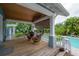 Charming covered patio with seating provides a tranquil view of the pool and garden at 5114 N Branch Ave, Tampa, FL 33603