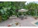 Outdoor dining area with table, chairs, umbrella, and a decorative fountain in a lush tropical backyard setting at 5114 N Branch Ave, Tampa, FL 33603