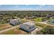 Aerial view of modern townhomes with rooftop patios amidst lush trees and a neighborhood pond at 6207 64Th N Way, Pinellas Park, FL 33781