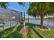 Landscaped backyard featuring a screened-in pool, mature trees, and a beautiful lake at 7328 Paradiso Dr, Apollo Beach, FL 33572