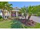 Charming home with lush landscaping, featuring mature palm trees and a well manicured lawn at 7328 Paradiso Dr, Apollo Beach, FL 33572