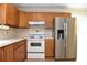 A modern kitchen features stainless steel refrigerator and white appliances, complemented by wooden cabinets at 7411 S Elliott St, Tampa, FL 33616