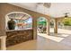 Covered outdoor kitchen featuring a stone bar, built-in grill, and seating area overlooking the pool at 7425 Terrace River Dr, Temple Terrace, FL 33637