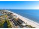 Beautiful aerial view showcasing beachfront homes and condos along a pristine sandy beach overlooking the ocean at 8083 Bayhaven Dr, Seminole, FL 33776