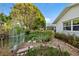 Idyllic backyard featuring beautiful foliage, stone walkway, and white exterior home with a garden gate at 8083 Bayhaven Dr, Seminole, FL 33776