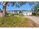 Inviting home exterior with a white facade, manicured yard, and a two-car garage, shaded by a mature tree at 8083 Bayhaven Dr, Seminole, FL 33776