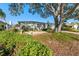 Beautiful front yard featuring stone benches, lush landscaping, and a charming white home with a two-car garage at 8083 Bayhaven Dr, Seminole, FL 33776
