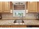 Kitchen features stainless steel sink, wooden cabinetry, granite countertops and window view at 8083 Bayhaven Dr, Seminole, FL 33776