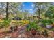 Lush backyard with mature trees, colorful flowers, and tranquil pond view at 110 Woods Landing Trl, Oldsmar, FL 34677