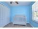 Light blue Bedroom features a white crib with closet and window, creating a calming and organized space at 11117 Abaco Island Ave, Riverview, FL 33579