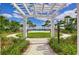 Inviting pool view through a pergola, showcasing a serene oasis surrounded by lush greenery and blue skies at 11117 Abaco Island Ave, Riverview, FL 33579