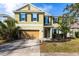 Two-story home featuring a two-car garage, well-maintained lawn, and freshly planted shrubbery under a clear, blue sky at 11539 Tangle Branch Ln, Gibsonton, FL 33534