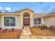 Inviting home entrance featuring an arched doorway with double doors, decorative landscaping, and a stone pathway at 1734 Kinsmere Dr, Trinity, FL 34655