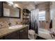 Bathroom featuring tiled walls, dark vanity, decorative mirror, and shower with nature-themed curtain at 1773 Ezelle Ave, Largo, FL 33770