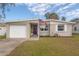 Charming single-story home featuring a manicured front lawn, single car garage, and a vibrant purple front door at 1773 Ezelle Ave, Largo, FL 33770