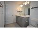 Bathroom with double sink vanity with gray cabinets and large framed mirror at 2411 Paravane Way, Wesley Chapel, FL 33543