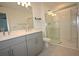 Bathroom featuring double sinks, grey cabinets, and glass-enclosed shower at 2411 Paravane Way, Wesley Chapel, FL 33543