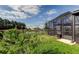 Spacious backyard featuring a screened lanai, lush greenery, and serene pond views at 34747 Telluride Ln, Zephyrhills, FL 33541
