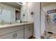 Bathroom featuring double sinks, granite countertops, soft gray cabinets, a large mirror, and a shower at 34747 Telluride Ln, Zephyrhills, FL 33541