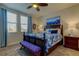 This bedroom features a dark wood bed with a patterned blue comforter, two windows, and a ceiling fan at 34747 Telluride Ln, Zephyrhills, FL 33541