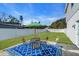 Backyard patio with a metal table set on a beautiful blue rug, all surrounded by a well-manicured lawn and white fence at 4053 11Th N Ave, St Petersburg, FL 33713