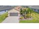 Charming home with an attached garage, paved driveway, and decorative palm trees in the front yard at 4920 Sevilla Shores Dr, Wimauma, FL 33598