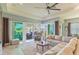 Open-concept living room with ample seating, neutral tones, and sliding glass doors to an outdoor patio at 4920 Sevilla Shores Dr, Wimauma, FL 33598