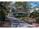Charming single-story home with lush landscaping and a paved driveway nestled among mature trees at 4964 Huntington Ne St, St Petersburg, FL 33703