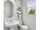 A half bathroom is nicely appointed with a stylish oval mirror and floating shelves above the toilet at 5526 Silver Sun Dr, Apollo Beach, FL 33572