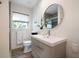 Well-lit bathroom with modern vanity, round mirror, toilet, and a window with natural light at 741 Mandalay Ave, Clearwater Beach, FL 33767