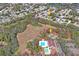 Aerial view showcasing community amenities, including pool and tennis courts near wooded areas and residential streets at 8204 Reynolds Dr, Hudson, FL 34667