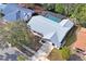 Aerial view showcases the property's layout, including a screened pool, lush landscaping, and roof at 8204 Reynolds Dr, Hudson, FL 34667