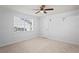 Bright bedroom features neutral carpet, white walls, ceiling fan, and window views at 8204 Reynolds Dr, Hudson, FL 34667