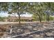 Exterior view of the Beacon Woods East Clubhouse, featuring a parking area shaded by mature trees at 8204 Reynolds Dr, Hudson, FL 34667