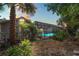 Inviting, screened pool illuminated at dusk, surrounded by lush tropical landscaping and a backyard setting at 8204 Reynolds Dr, Hudson, FL 34667