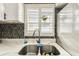 Close-up of kitchen sink showcasing stainless steel fixtures and contrasting tiled backsplash at 9201 Lunar Ln, Port Richey, FL 34668